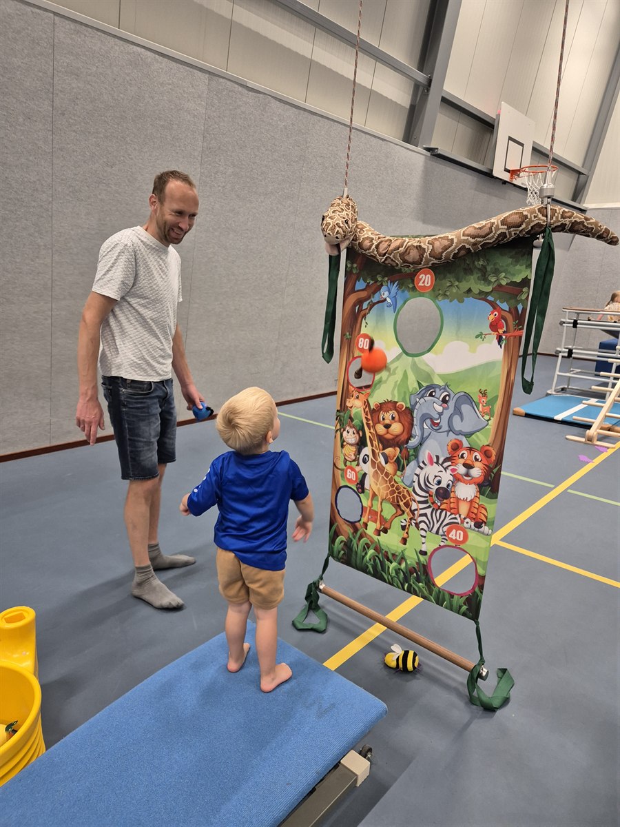 Vader en kind die samen een spel doen tijdens de gymles