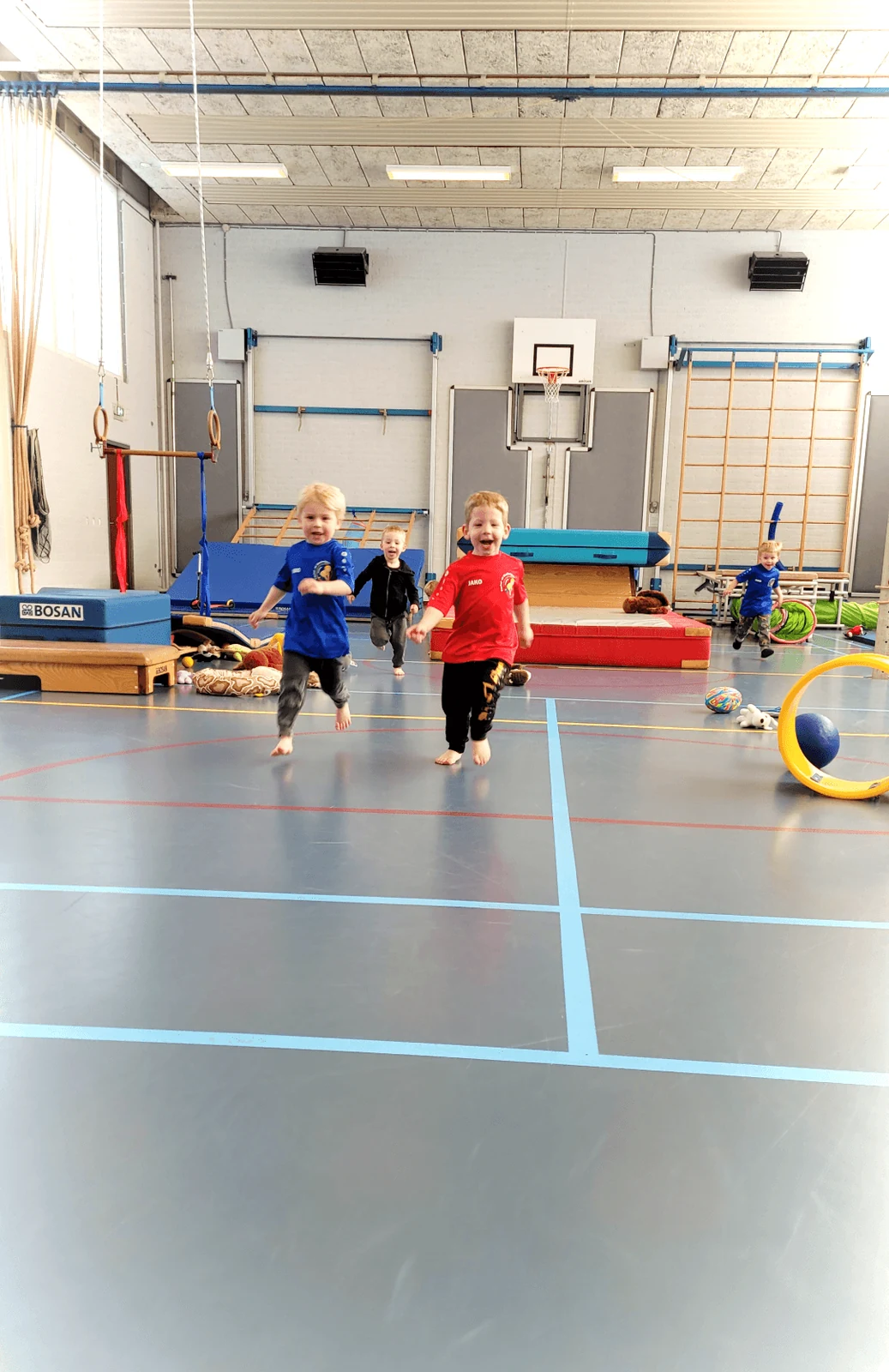 Een groep kinderen die samen door de gymzaal rent