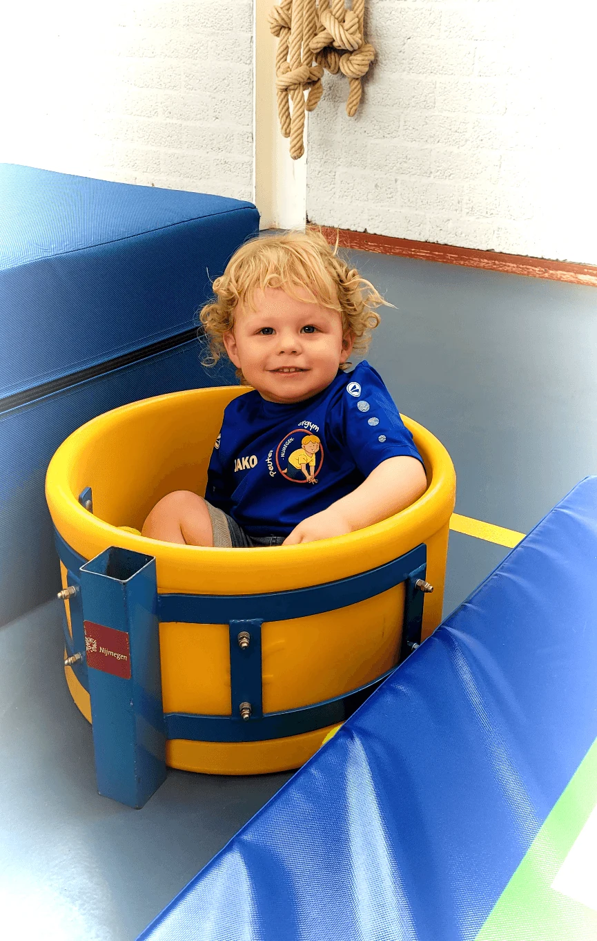 Dreumes die met plezier in een gele gymton zit