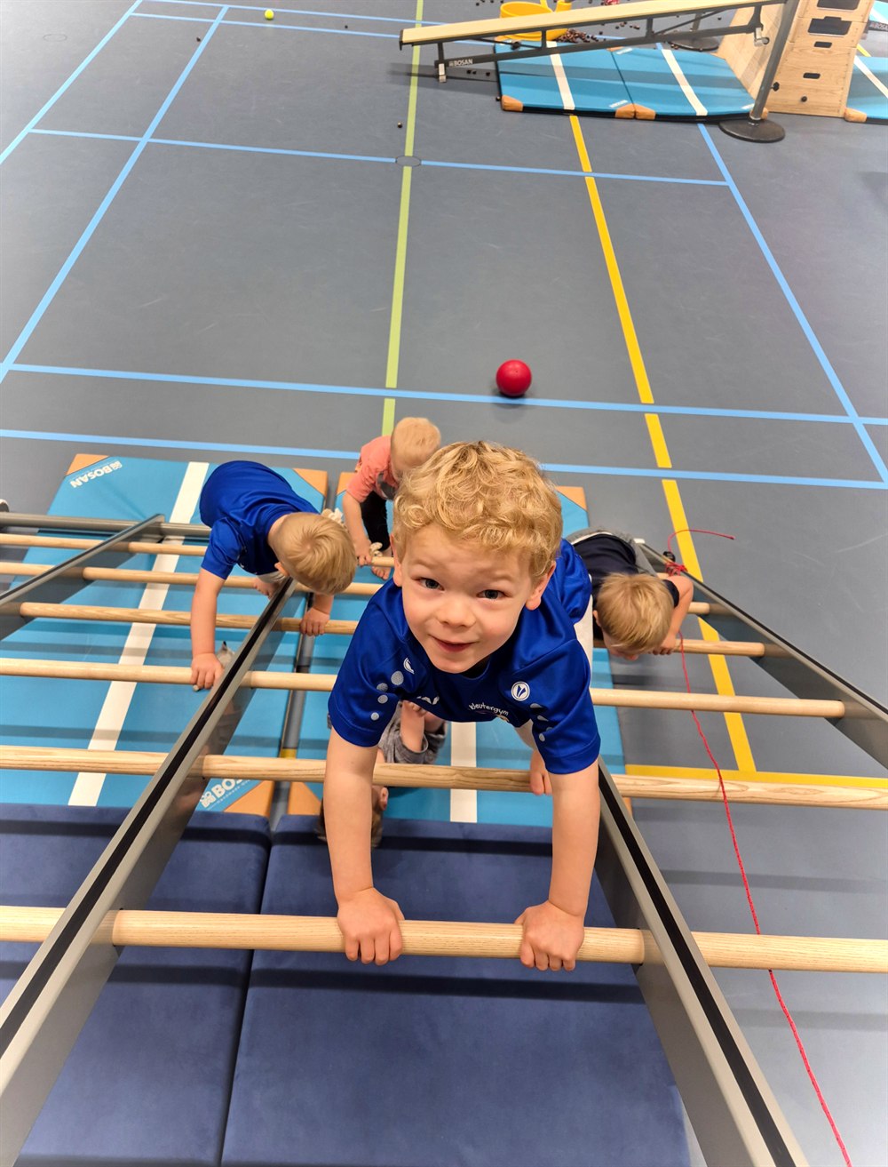 Kinderen die samen over een klimtoestel bewegen tijdens de gymles