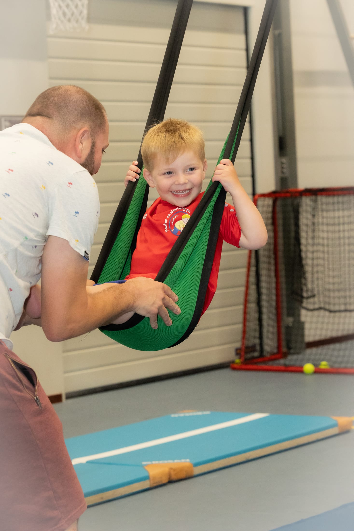 Ouder die zijn kind begeleidt tijdens een oefening in de gymles