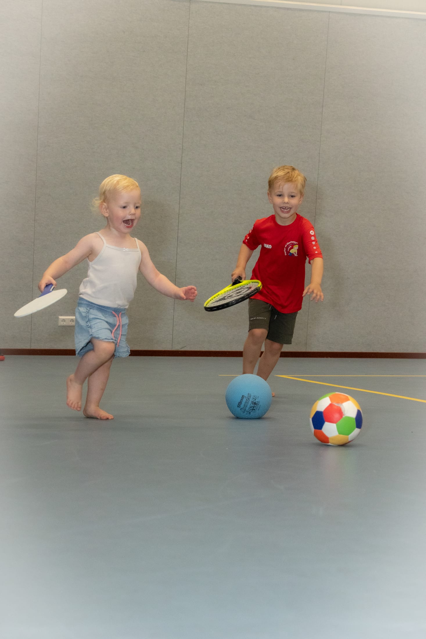 Broertje en zusje die samen met rackets en ballen bewegen