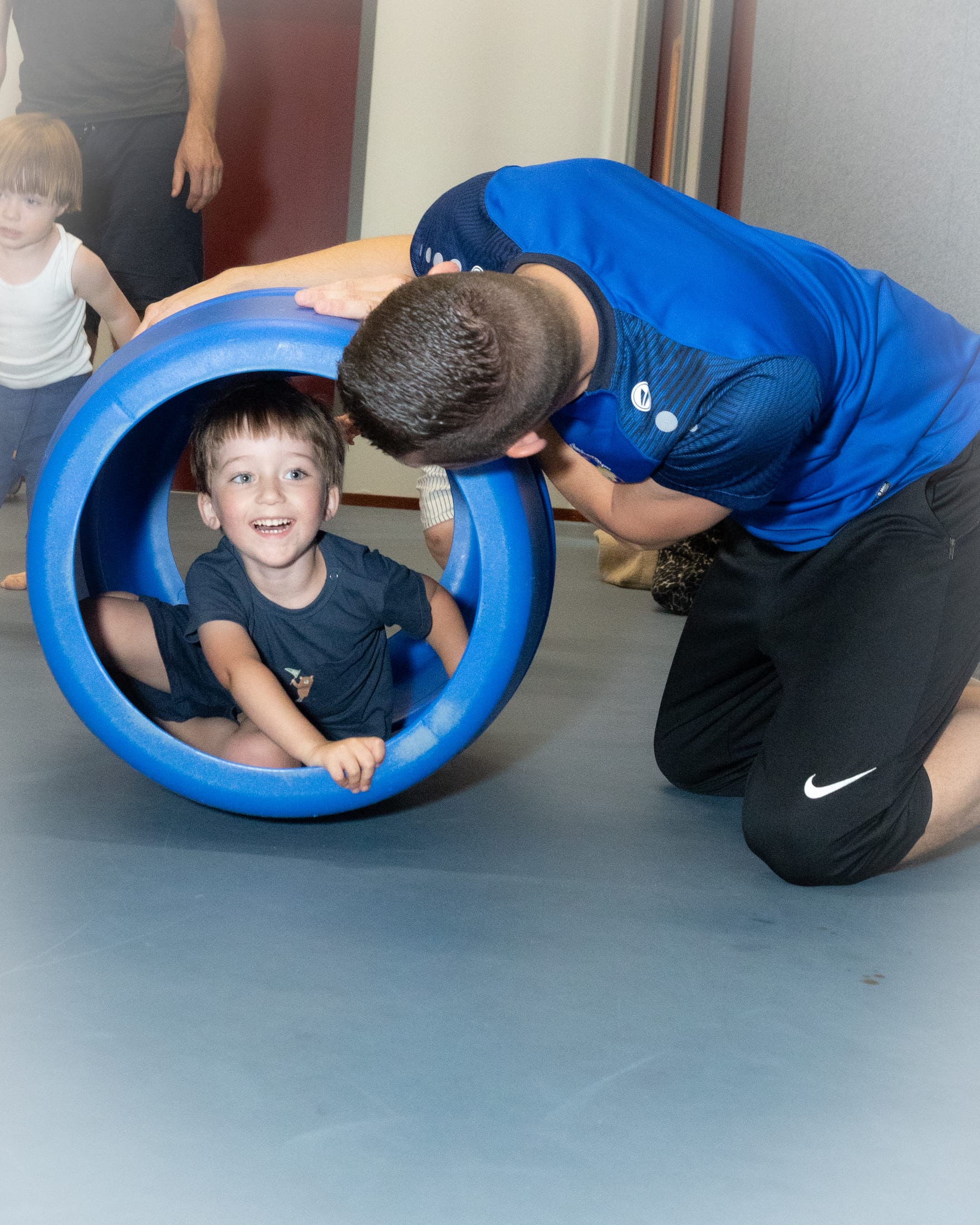 Gymleider die een kind helpt tijdens de peuter- en kleutergym